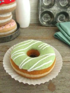 a green donut sitting on top of a paper plate next to a muffin tin