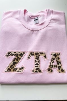 a pink t - shirt with leopard print on the front and letters across the chest