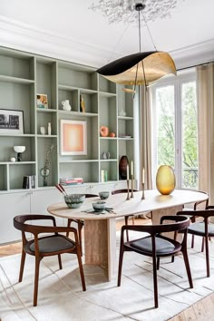 the dining room table is surrounded by chairs and bookshelves with open shelving behind it