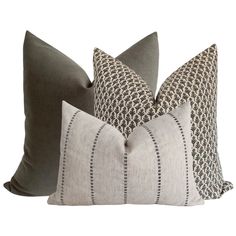 three pillows with different patterns on them, one in grey and the other in white