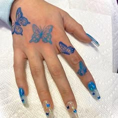 a woman's hand with blue butterfly tattoos on her left hand and two fingers