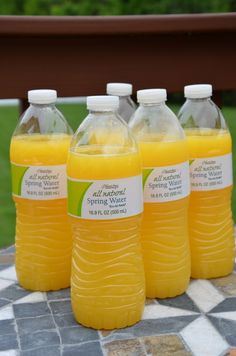 four bottles of orange juice sitting on top of a table