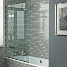 a bathroom with gray tiles and white fixtures, including a tub shower and toilet in the corner