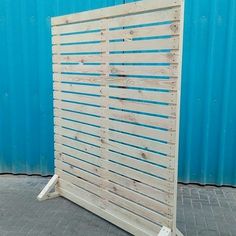 a large wooden slatted screen sitting on top of a brick floor next to a blue wall