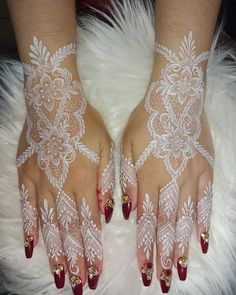 a woman's hands with white lace on them and red fingernails, both decorated with gold glitters