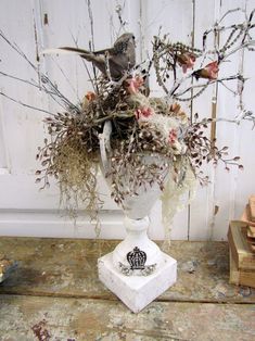 a white vase filled with lots of flowers on top of a table