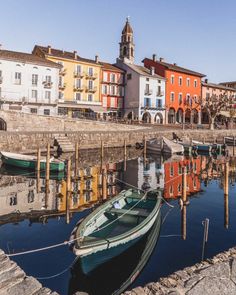 a small boat is docked in the water next to some colorful buildings and cobblestone streets