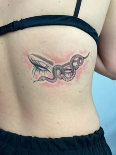 a woman's stomach with a snake tattoo on her lower back, and an eye in the middle