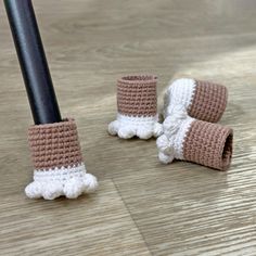 two crocheted baby booties sitting on the floor next to a black pole