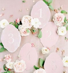 the table numbers are laid out with flowers on them and leaves scattered around each number