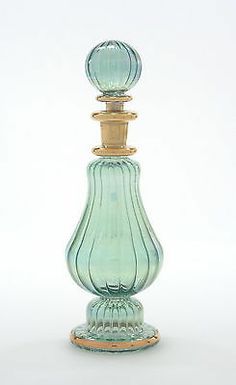 a green glass perfume bottle sitting on top of a white table