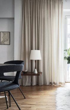 an image of a living room with white curtains and black chairs in front of the window