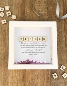 a scrabble frame sitting on top of a wooden table with letters spelling sister