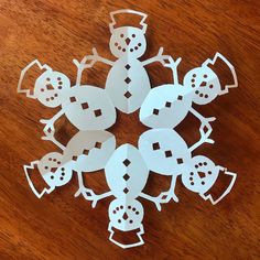 paper cut snowmen on a wooden table