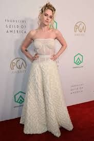 a woman standing on top of a red carpet wearing a white strapless dress and holding her hands on her hips