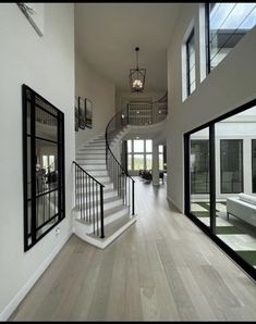 an open floor plan with white walls and wood floors, black railings and glass doors