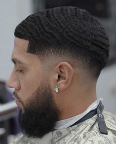 a close up of a person with a haircut and a beard wearing an earring