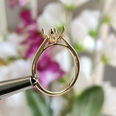 a close up of a gold ring with flowers in the background