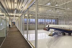 an airplane is parked in the middle of a large room with glass walls and windows