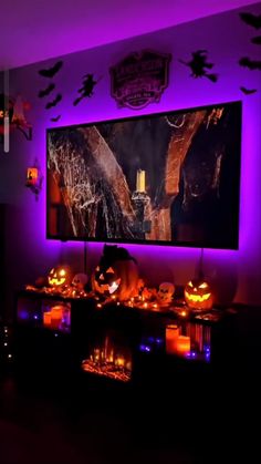 a living room decorated for halloween with purple lighting and pumpkins on the table in front of it