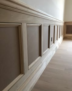 an empty room with wood paneling on the wall and wooden floors in front of it