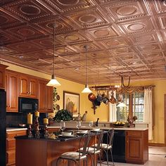 an open kitchen and dining room with metallic ceiling tiles on the ceiling, along with wooden cabinets