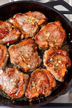 pork chops cooking in a skillet on top of a stove with seasoning