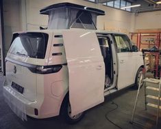 a white van parked in a garage with its door open and it's hood up