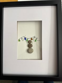 a white frame holding a rock and some string