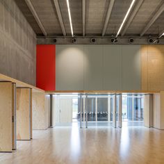 an empty room with wooden floors and red wall in the center, surrounded by partitions