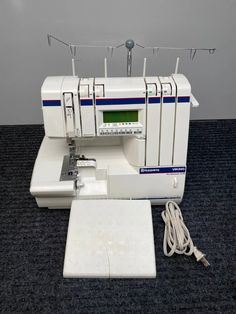 a white sewing machine sitting on top of a blue carpet next to a power strip