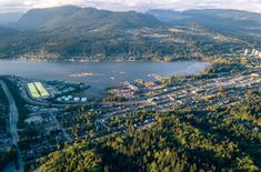 an aerial view of a city with mountains in the background and trees around it,