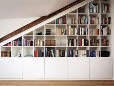 a bookshelf filled with lots of books next to a stair case in a room