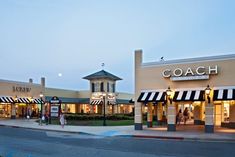 a coach store on the corner of a street in front of a building with black and white striped awnings