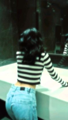 a woman standing in front of a bathroom mirror with her back turned to the camera