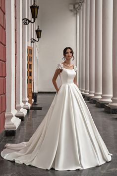 a woman in a white wedding dress standing on the floor next to columns and pillars