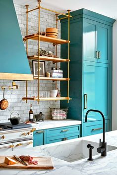 a kitchen with blue cabinets and white marble counter tops, an open shelving unit above the stove