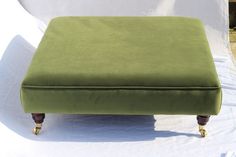 a green footstool sitting on top of a white sheet