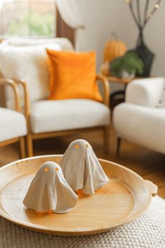 two small white figurines sitting on top of a wooden tray in a living room