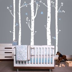 a baby's room with white birch trees and blue birds