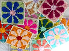 several crocheted squares are arranged on a white surface, each with different colors