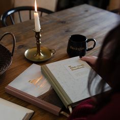 a person sitting at a table with a book and candle