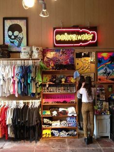 a woman standing in front of a store filled with clothes and t - shirt items