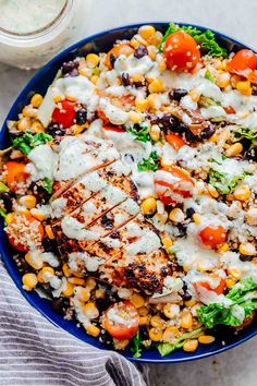 a blue bowl filled with chicken, salad and dressing