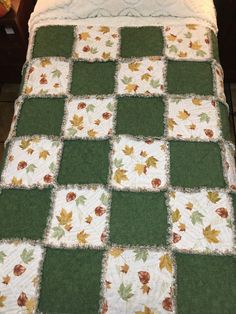 a green and white quilted bedspread with leaves on the bed topper