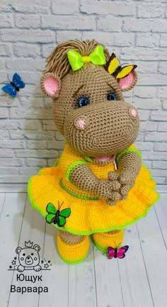 a crocheted stuffed animal in a yellow dress with butterflies around it's neck