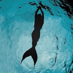 a woman is silhouetted in the water with her arms up and hands behind her back