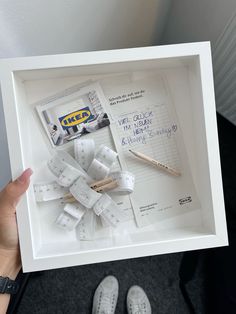 a person holding up a framed photo with scissors and tape