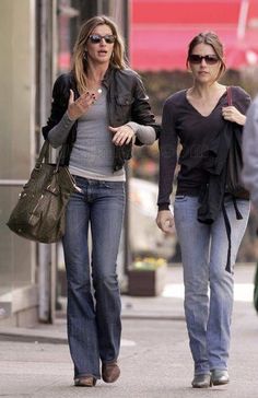 two women walking down the street with one holding her hand and another pointing at something