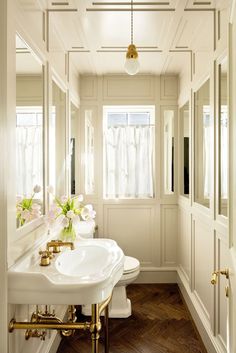 a bathroom with white walls and wood flooring next to a sink, toilet and mirror